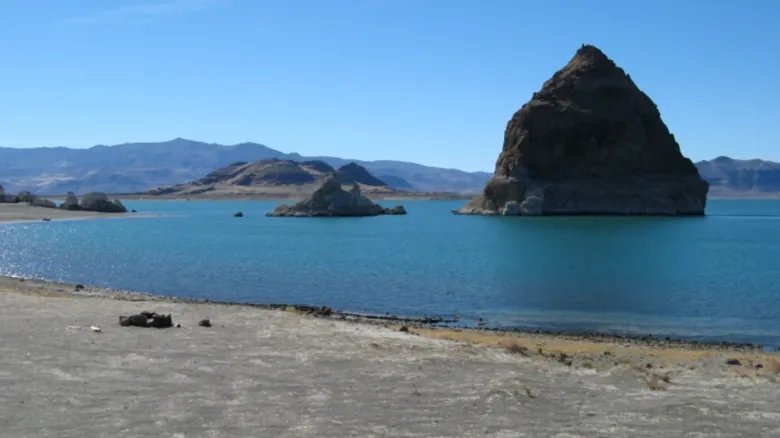 A photo of Pyramid Lake taken from the shoreline showing a large pyramid-like tufa on a nearby island